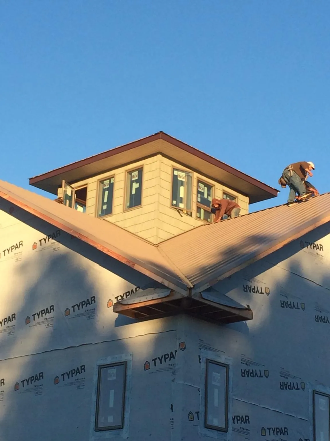 Roofers working around a rooftop cupola on a new metal roof at sunset — Roof Waterproofing in Gaston by Roofing Brothers